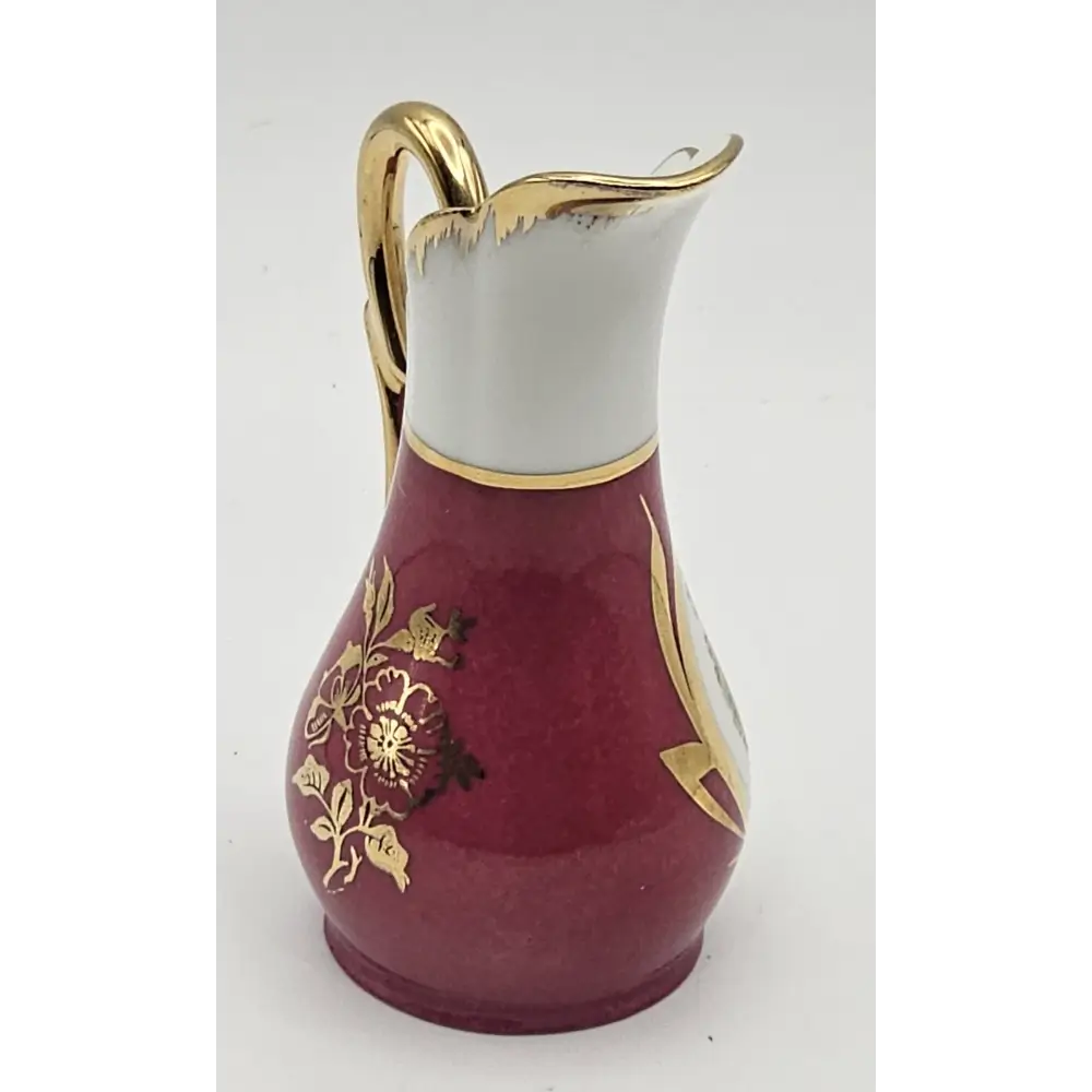 Decorative ceramic pitcher with gold floral patterns on a white background