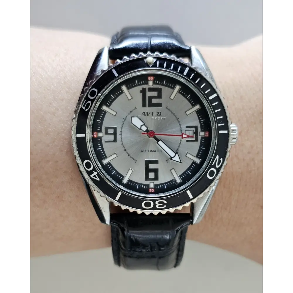 Wrist wearing a black wristwatch with a silver face