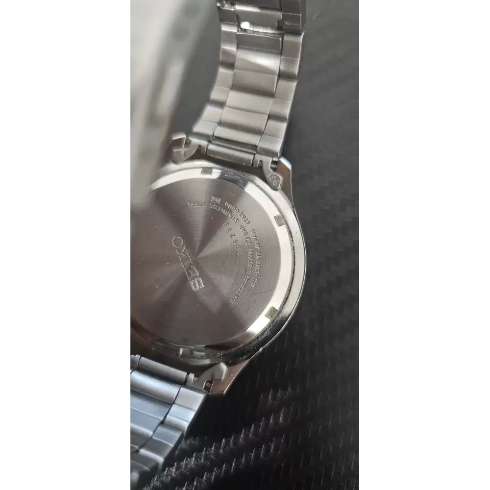 Close-up of a silver watch with brand name on a textured black surface