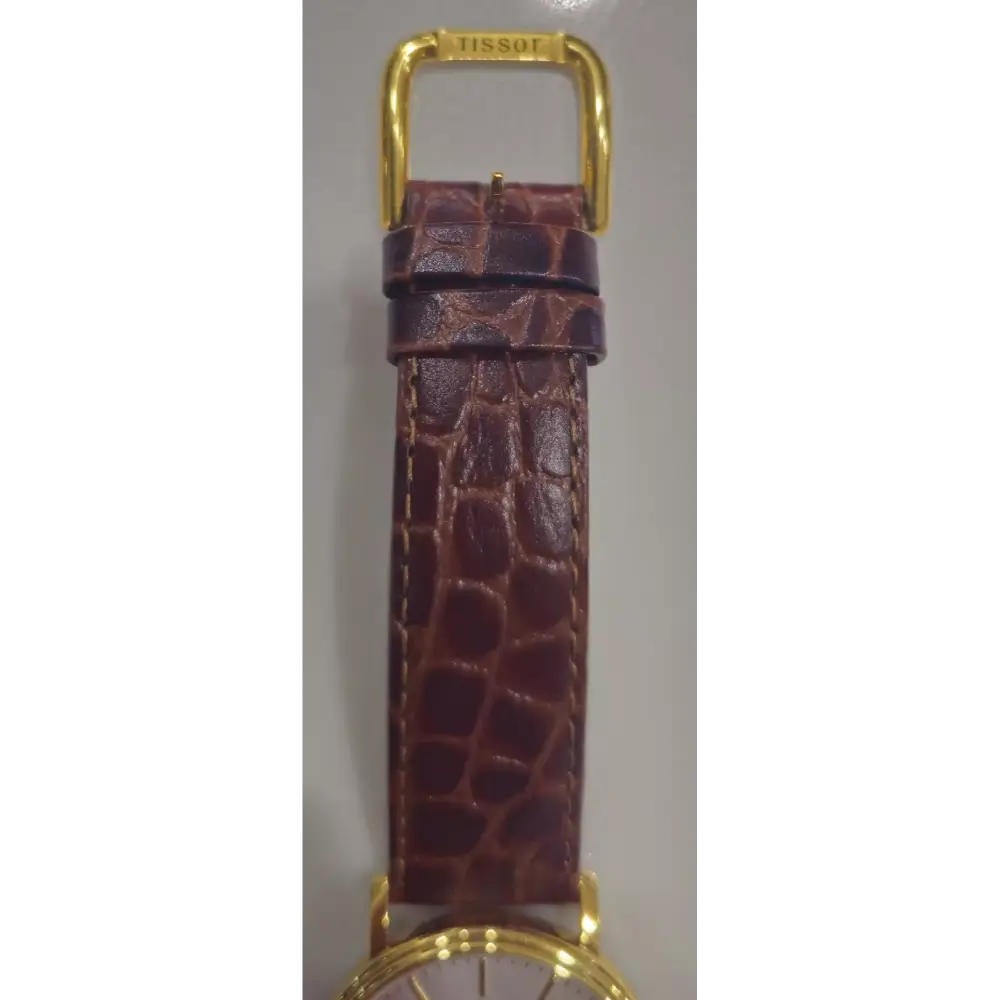 Brown crocodile-patterned leather strap with gold hardware on a gray background