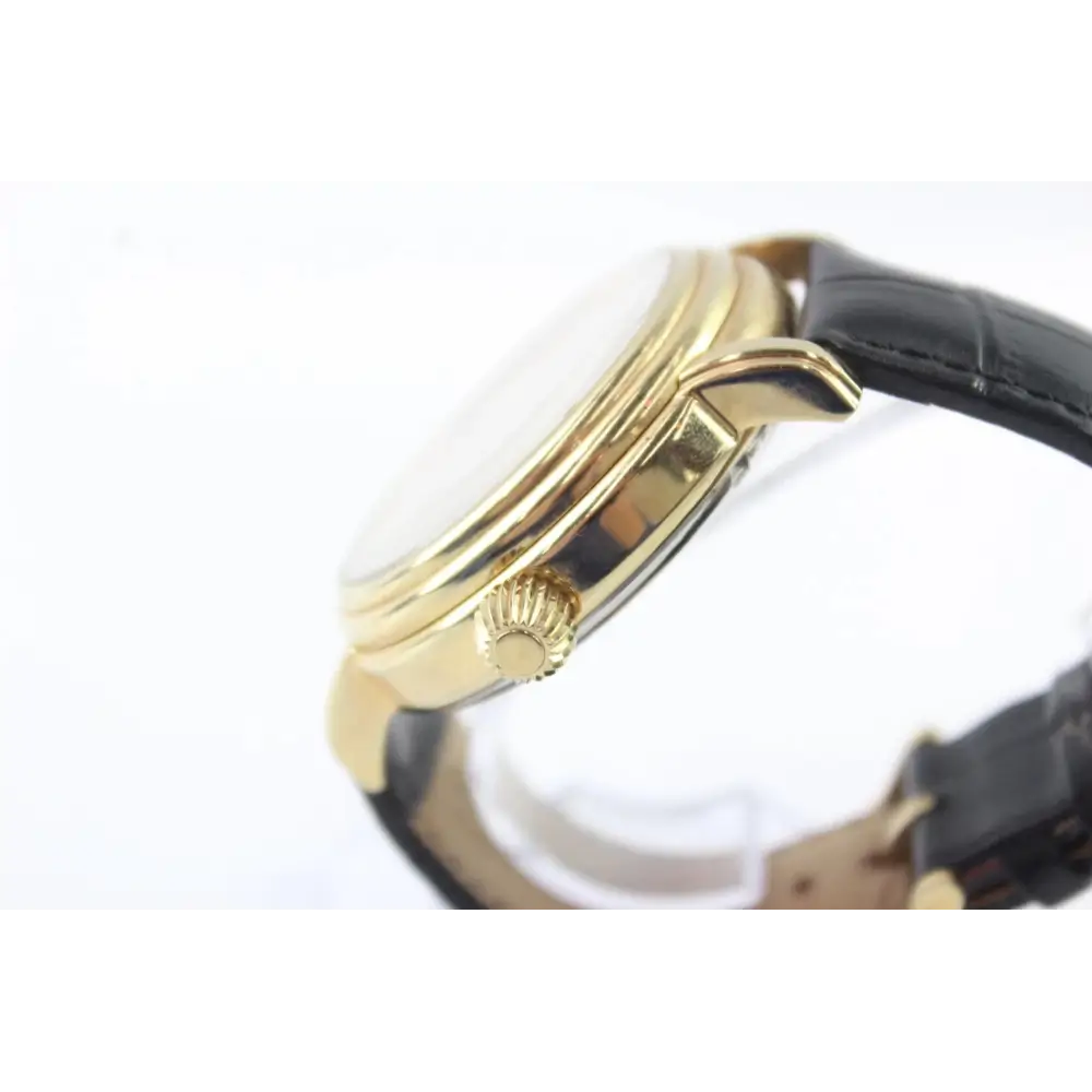 Close-up of a gold watch with a black strap