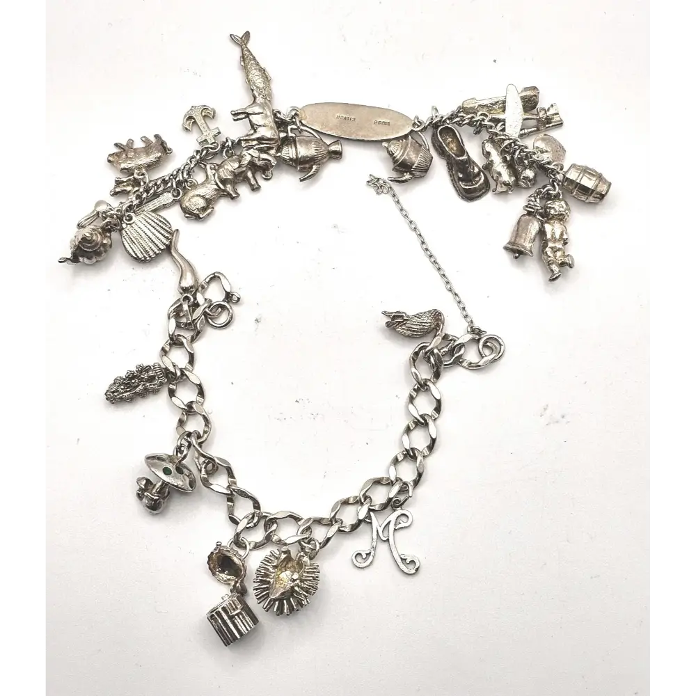 Silver charm bracelet with various charms on a white background
