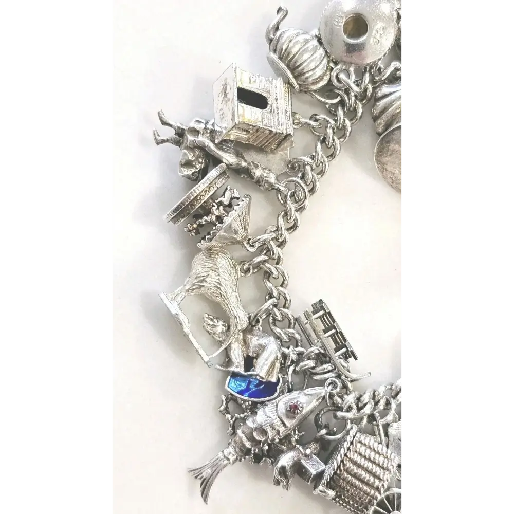 Silver charm bracelet with various charms on a white background