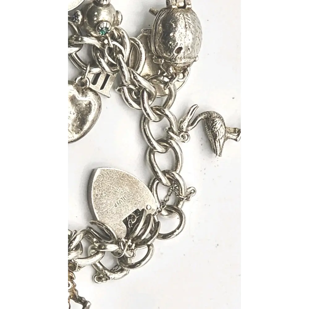 Silver charm bracelet with various charms on a white background