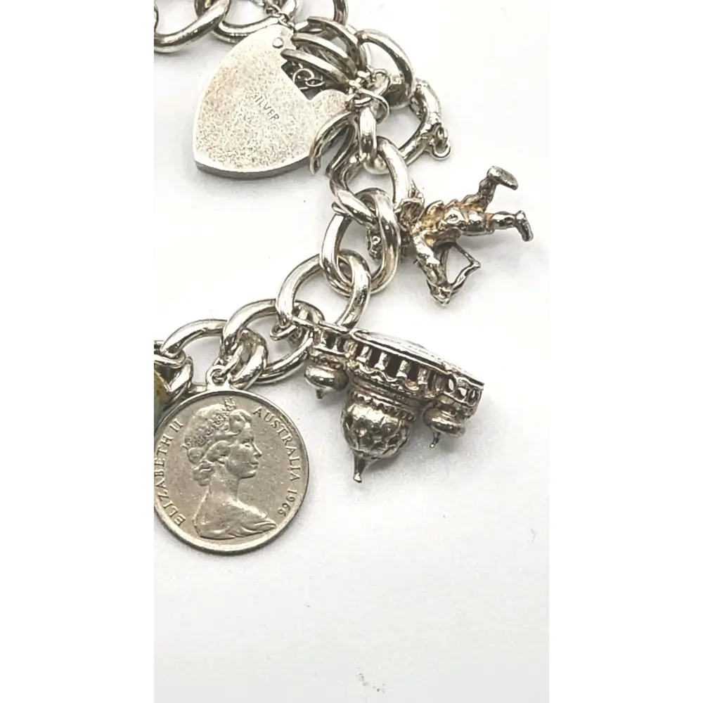 Silver charm bracelet with various charms on a white background
