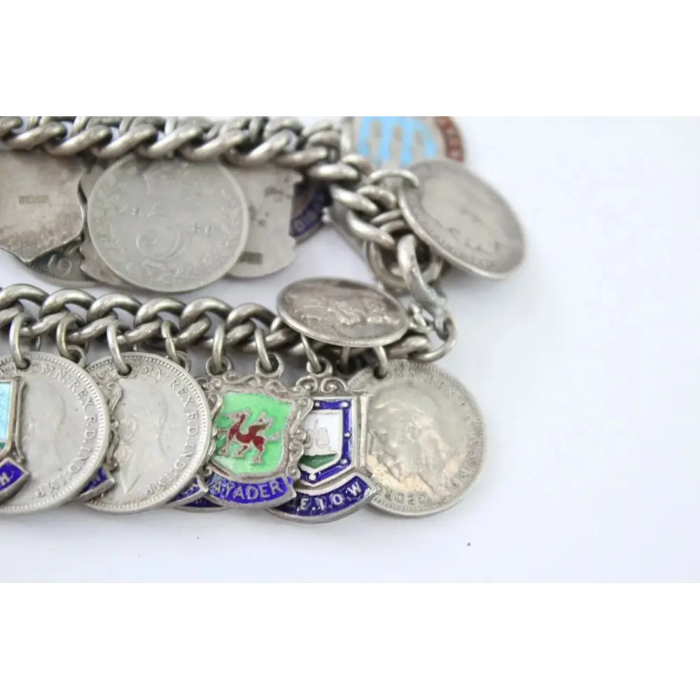 Silver charm bracelet with various coins and charms on a white background