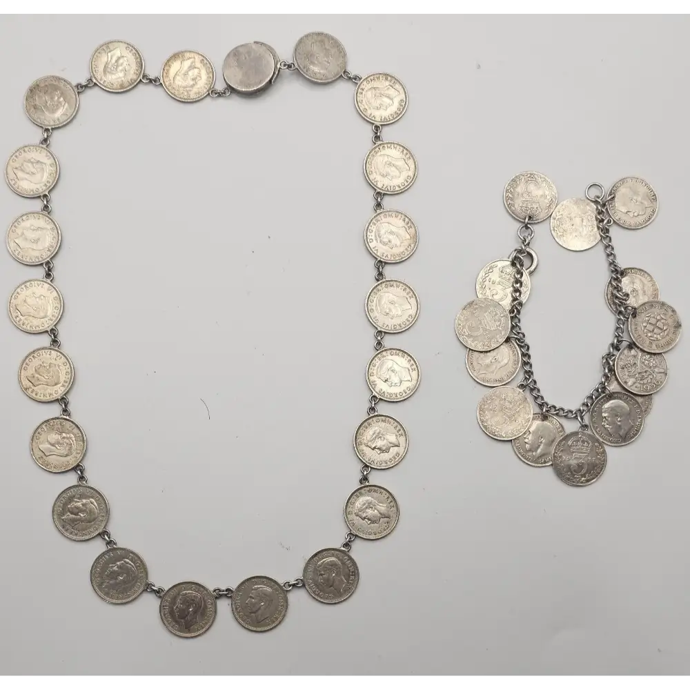 Silver coin necklace and bracelet on a light gray background