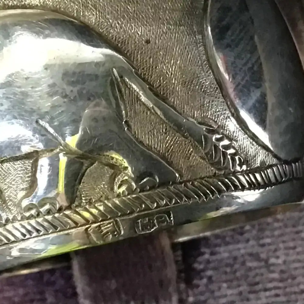 Close-up of a metallic object with engraved design on a textured surface
