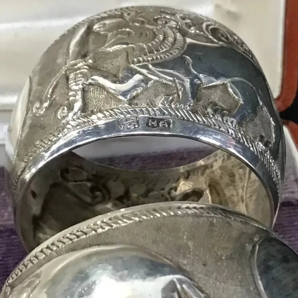 Silver ring with intricate designs and engravings on a white background