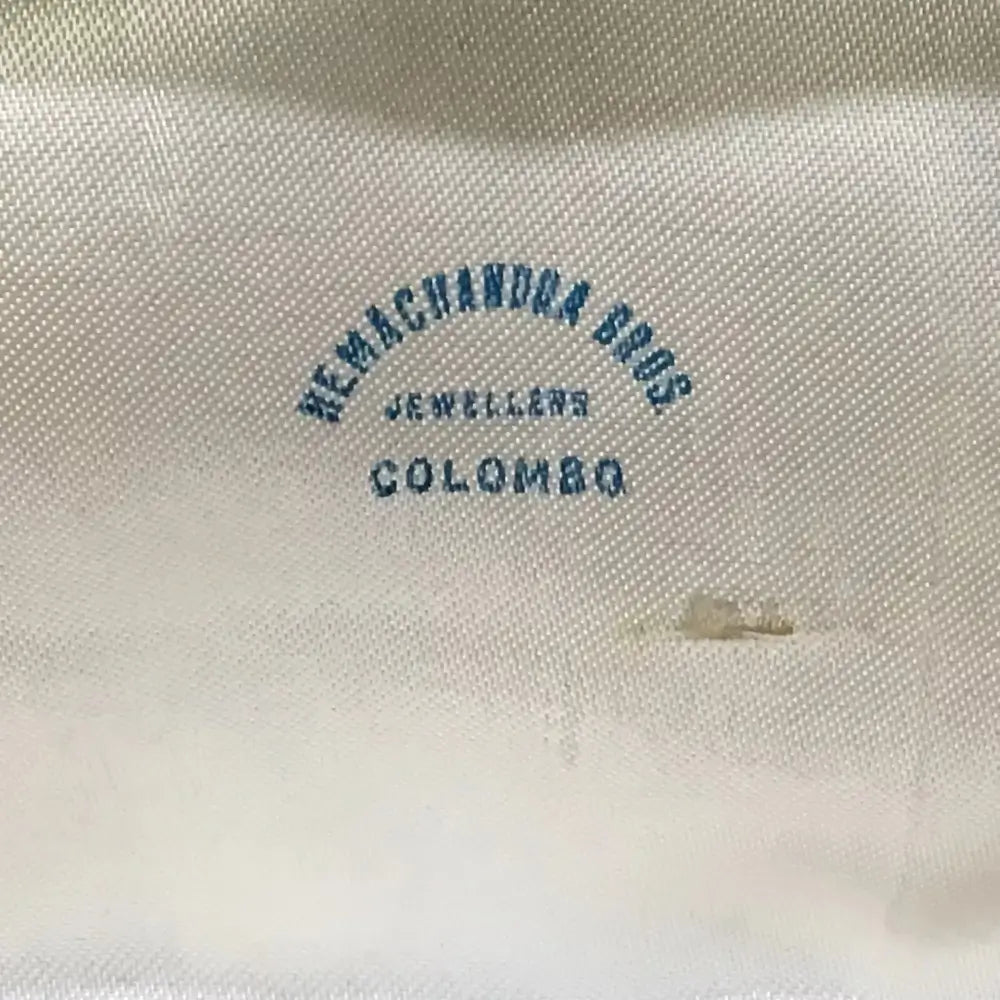Text 'REMACHANDRA BROS JEWELLERS COLOMBO' on a textured beige background