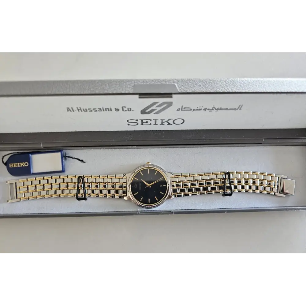 Gold Seiko watch with black face on a white background