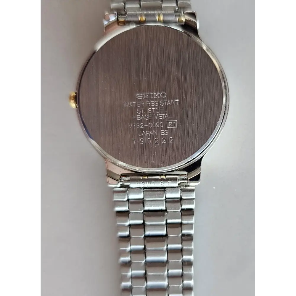 Back view of a Seiko watch with metal band on a light gray background