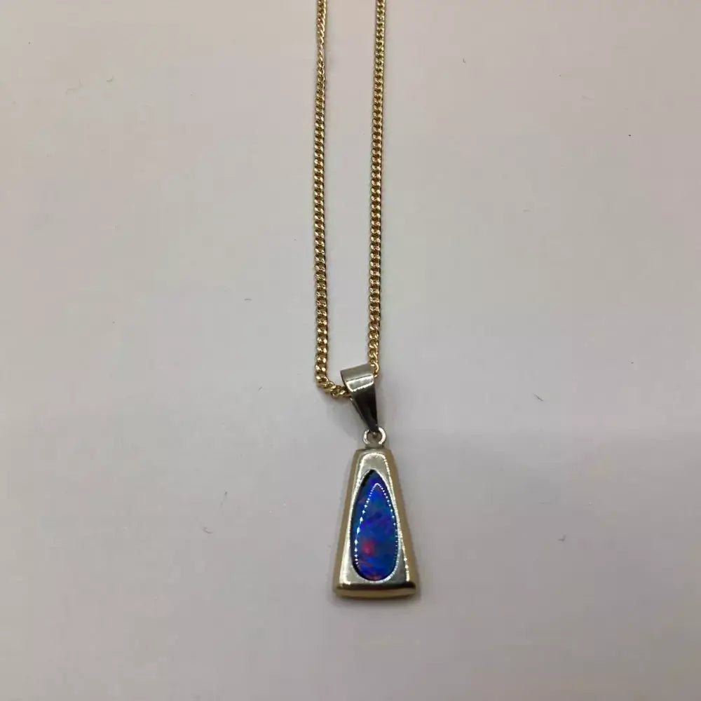 Gold necklace with a triangular pendant featuring blue and red colors on a light gray background