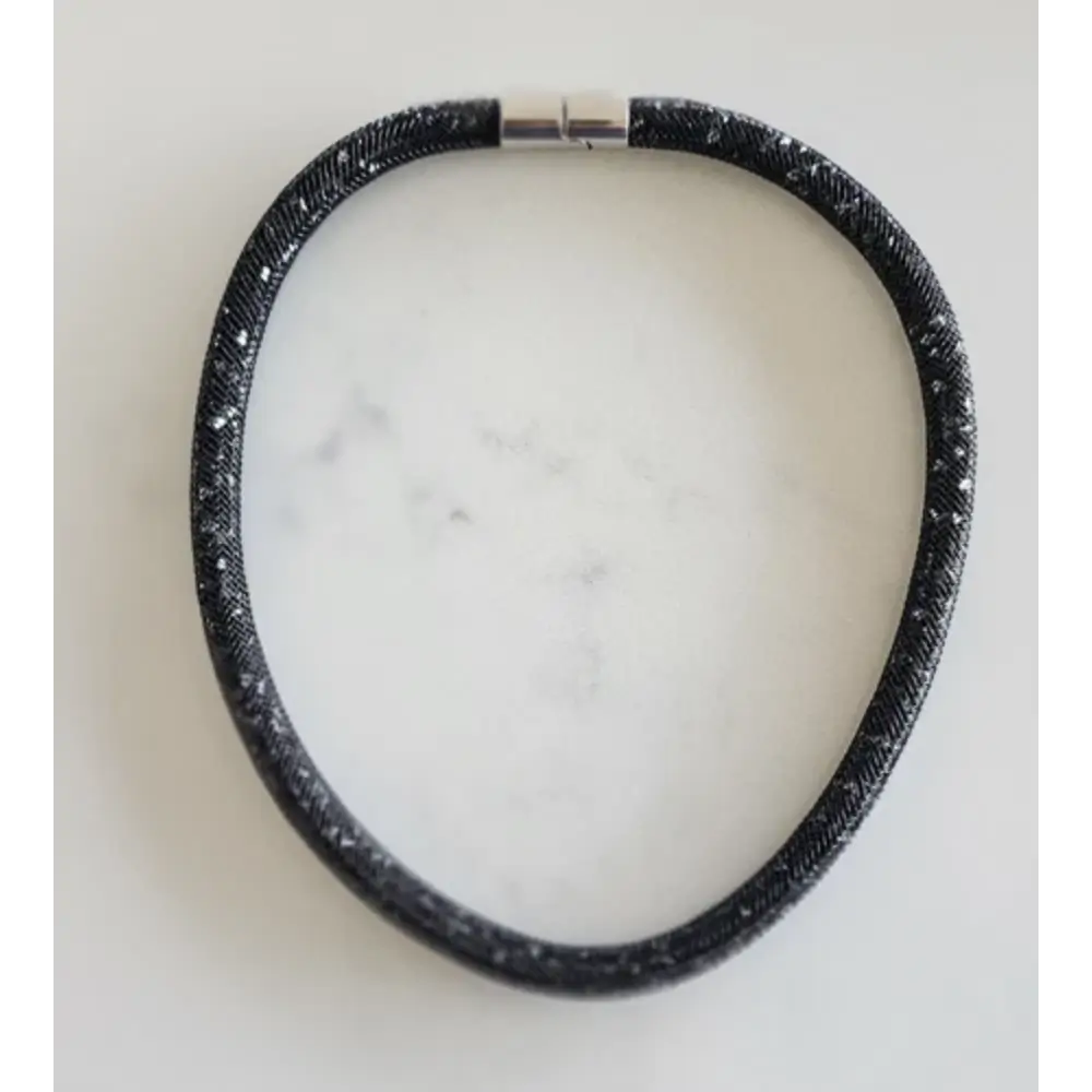 Black textured Necklace on a white marble surface