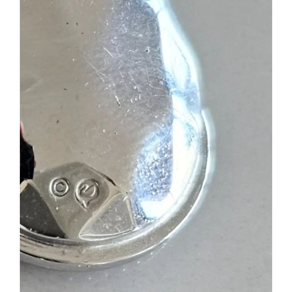 Close-up of a silver object with visible hallmarks on a gray background
