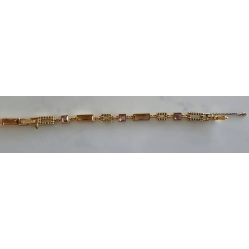 Gold bracelet with pink stones on a white background
