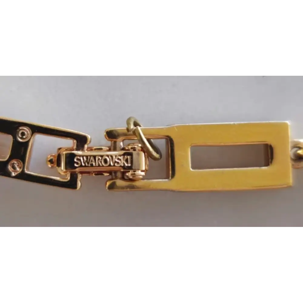 Gold and black Swarovski clasp on a gray background