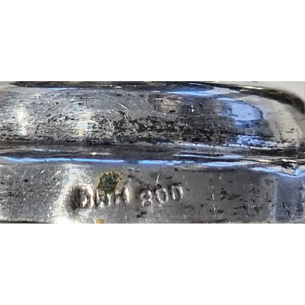Close-up of a glass object with 'DAM 200' marking on a white background