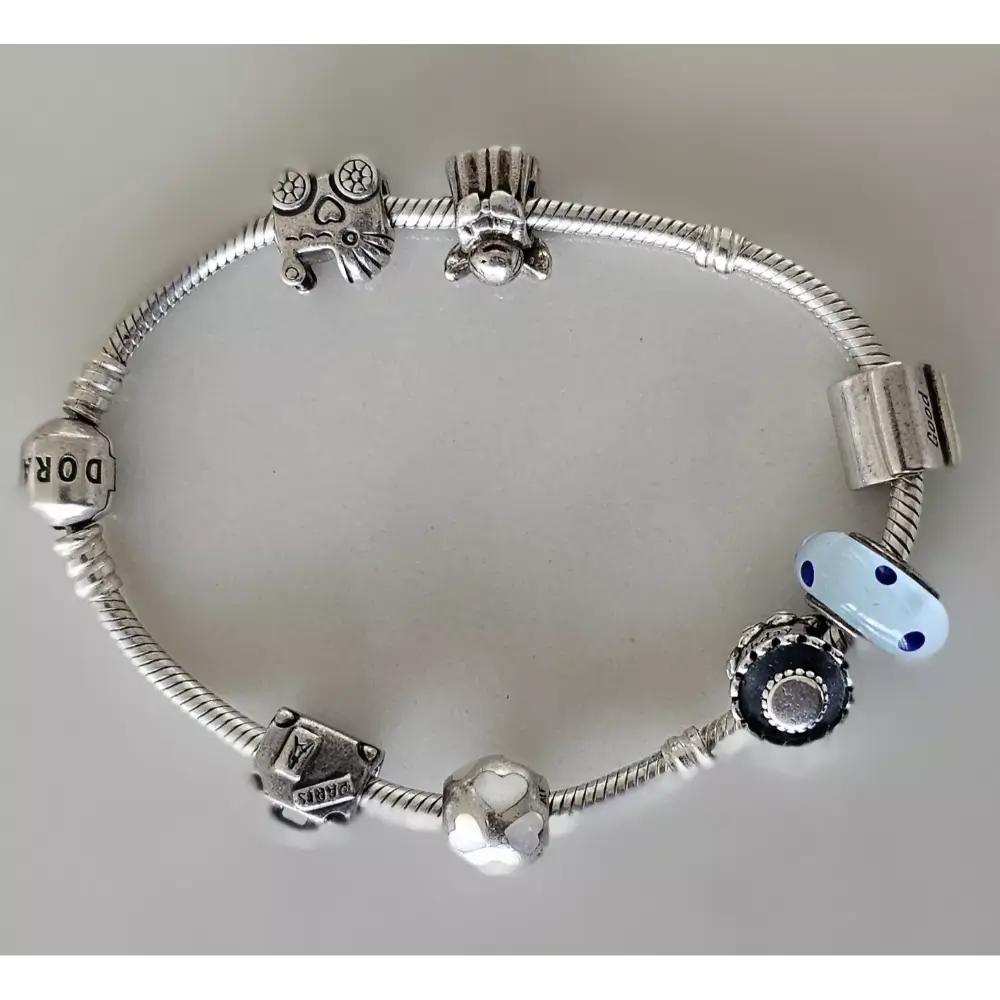 Silver charm bracelet with various charms on a light gray background