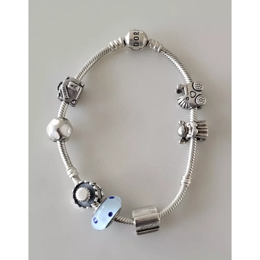 Silver bracelet with various charms on a light gray background