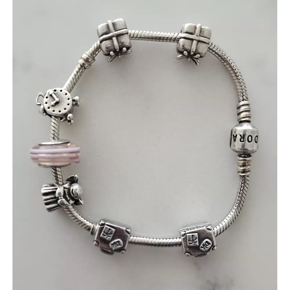 Silver charm bracelet with various charms on a light gray background