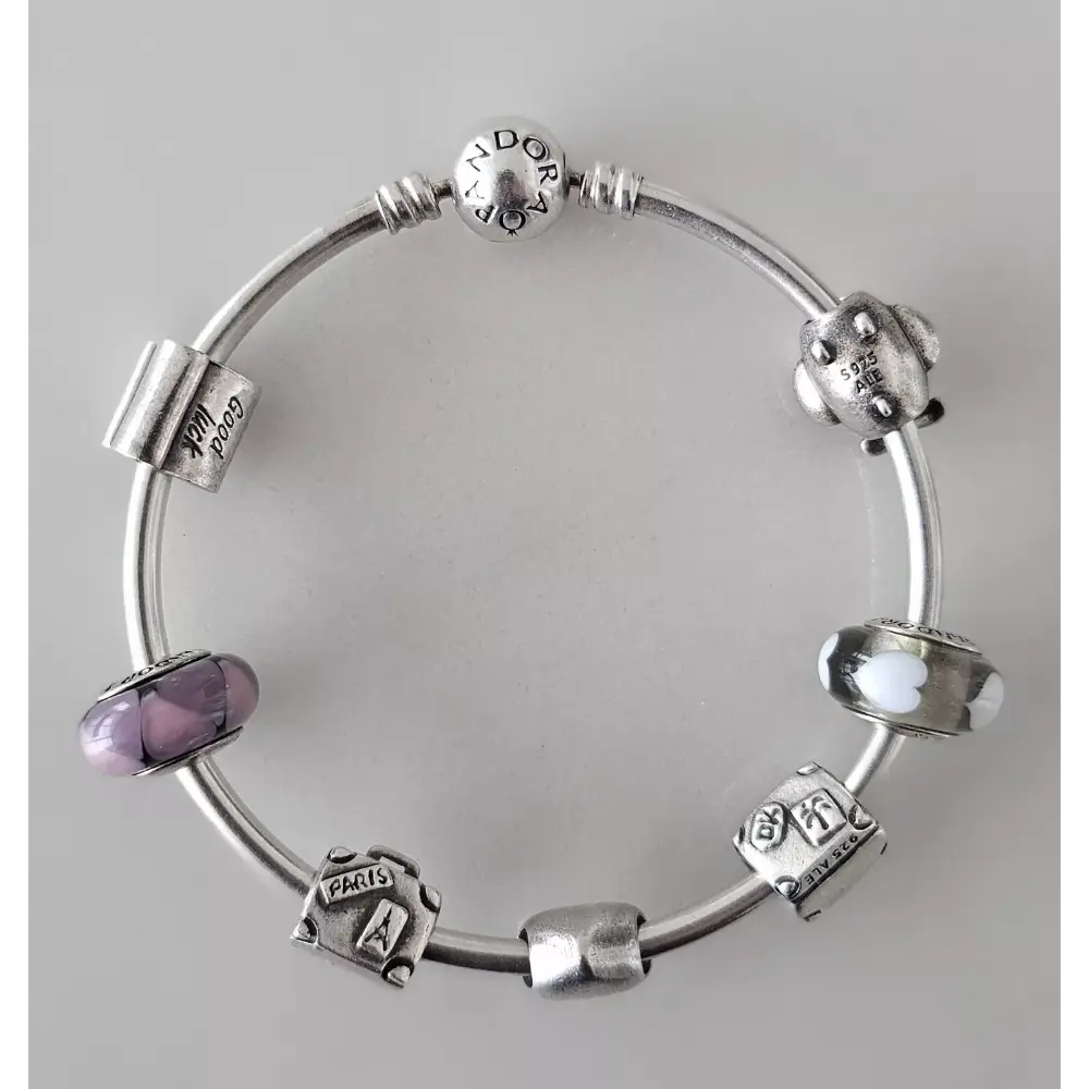 Silver bracelet with various charms on a gray background