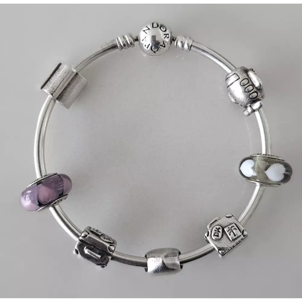 Silver bracelet with various charms on a gray background