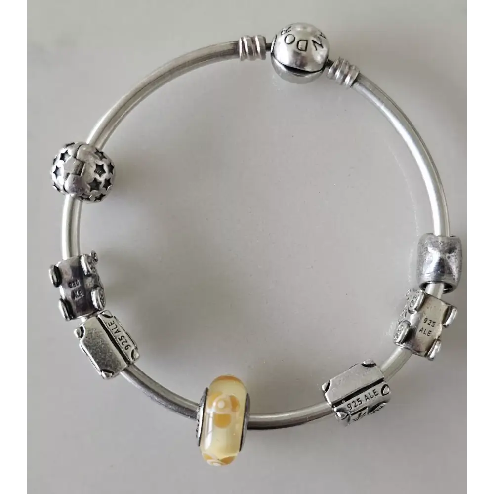 Silver bracelet with various charms on a light gray background