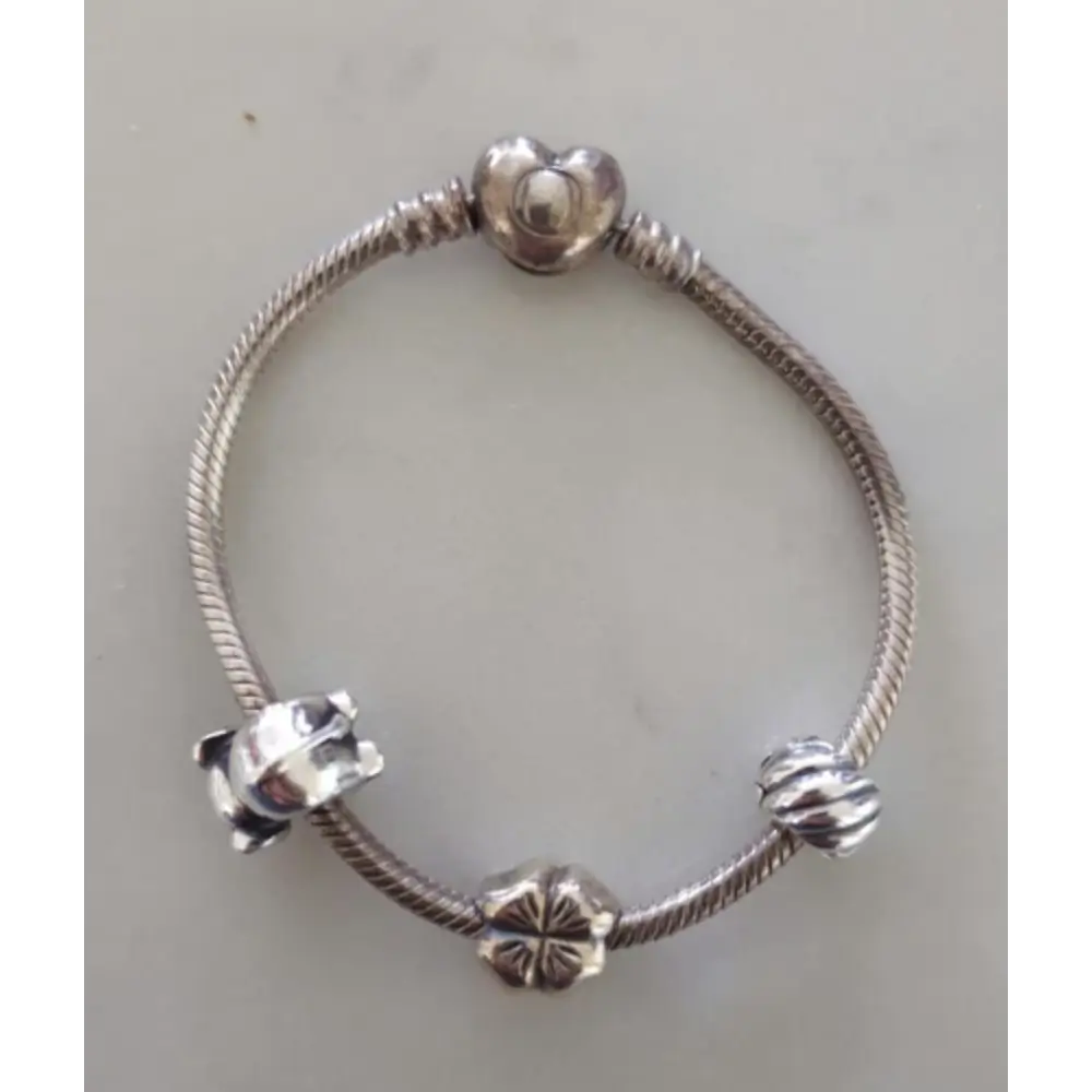 Silver bracelet with various charms on a light gray background