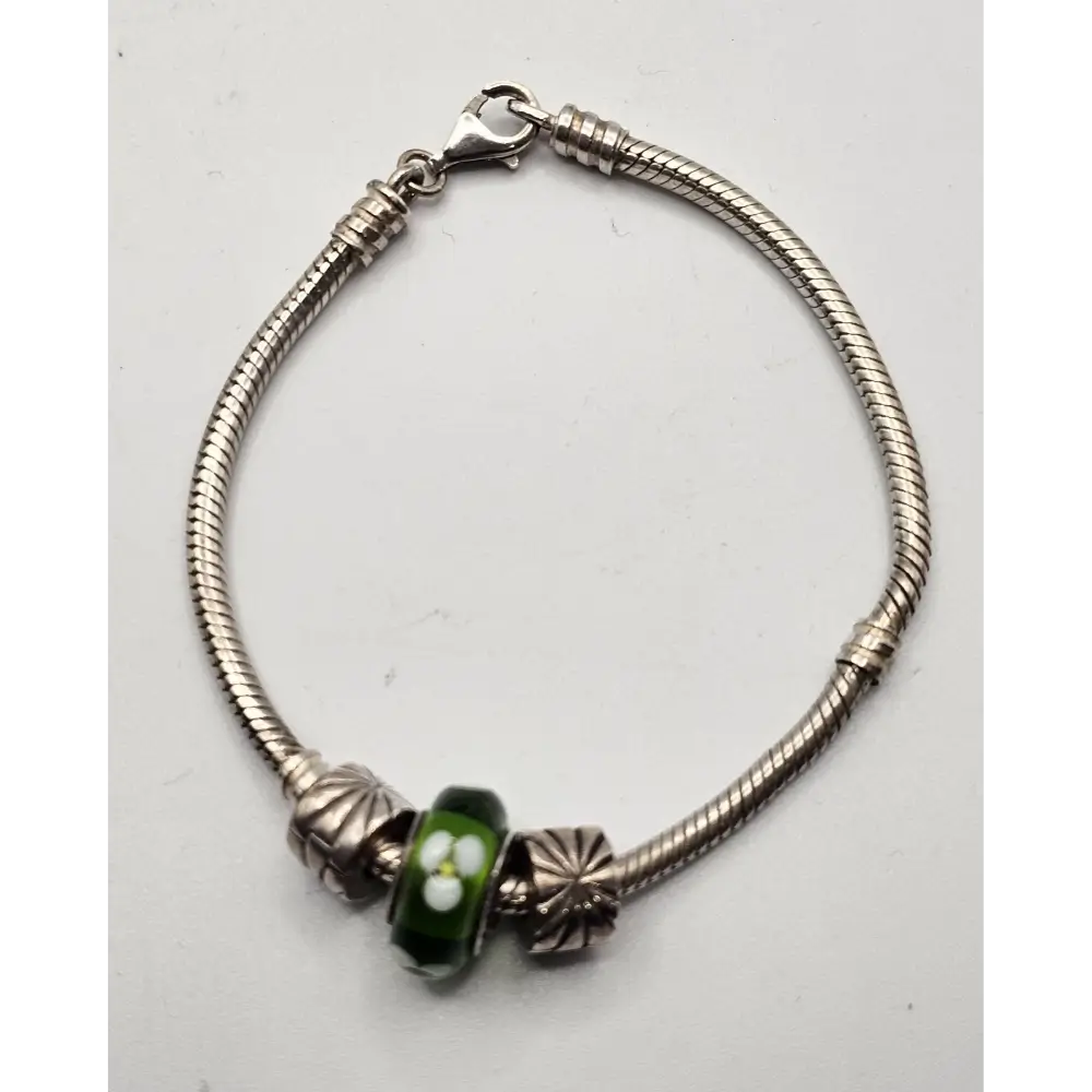 Silver bracelet with a green bead on a white background