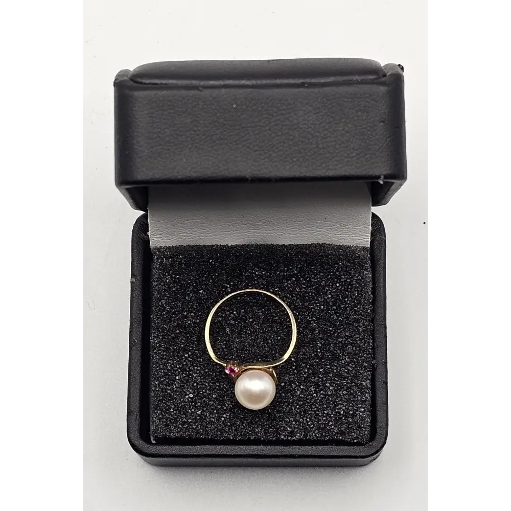 Gold ring with a pearl and ruby in a black jewelry box