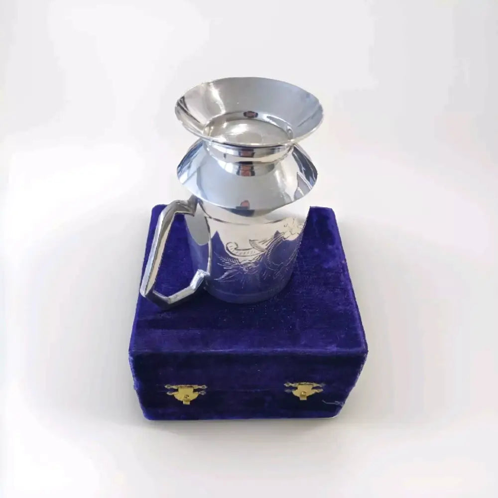 Silver teapot on a purple velvet box against a white background