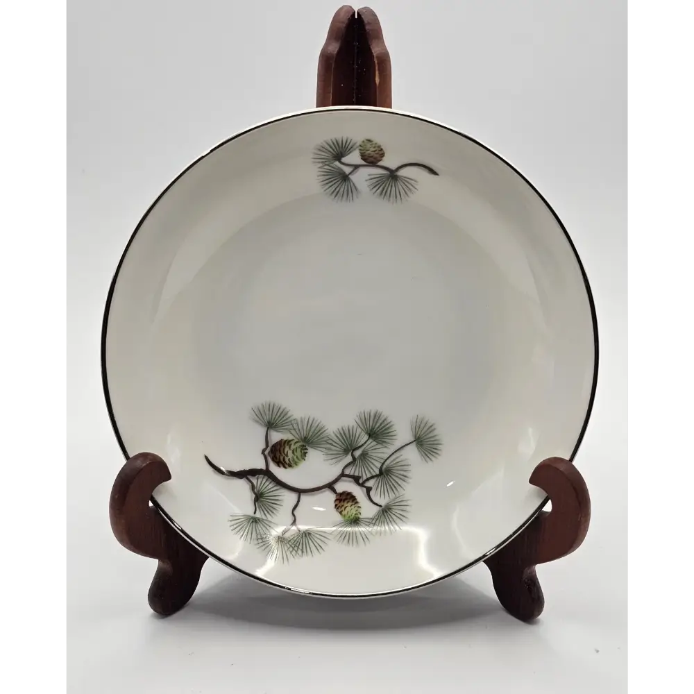Ceramic bowl with pine branch design on a wooden stand