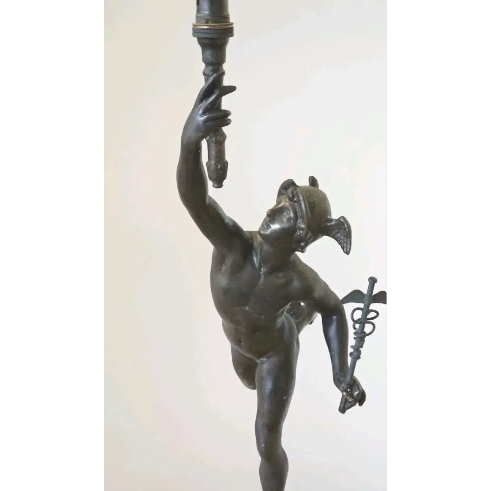 Bronze statue of a figure holding a torch against a white background