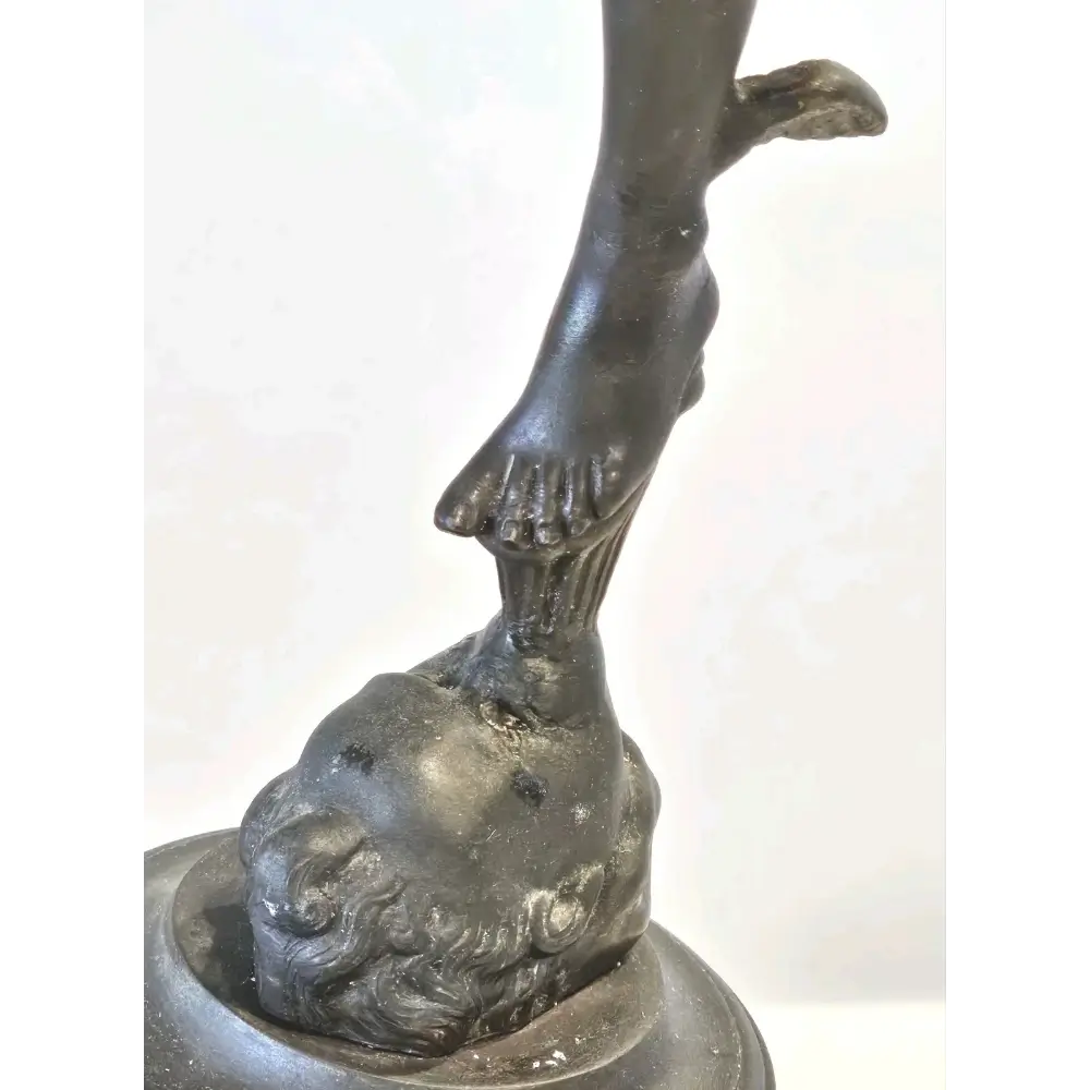 Bronze sculpture of a figure with outstretched arm and foot