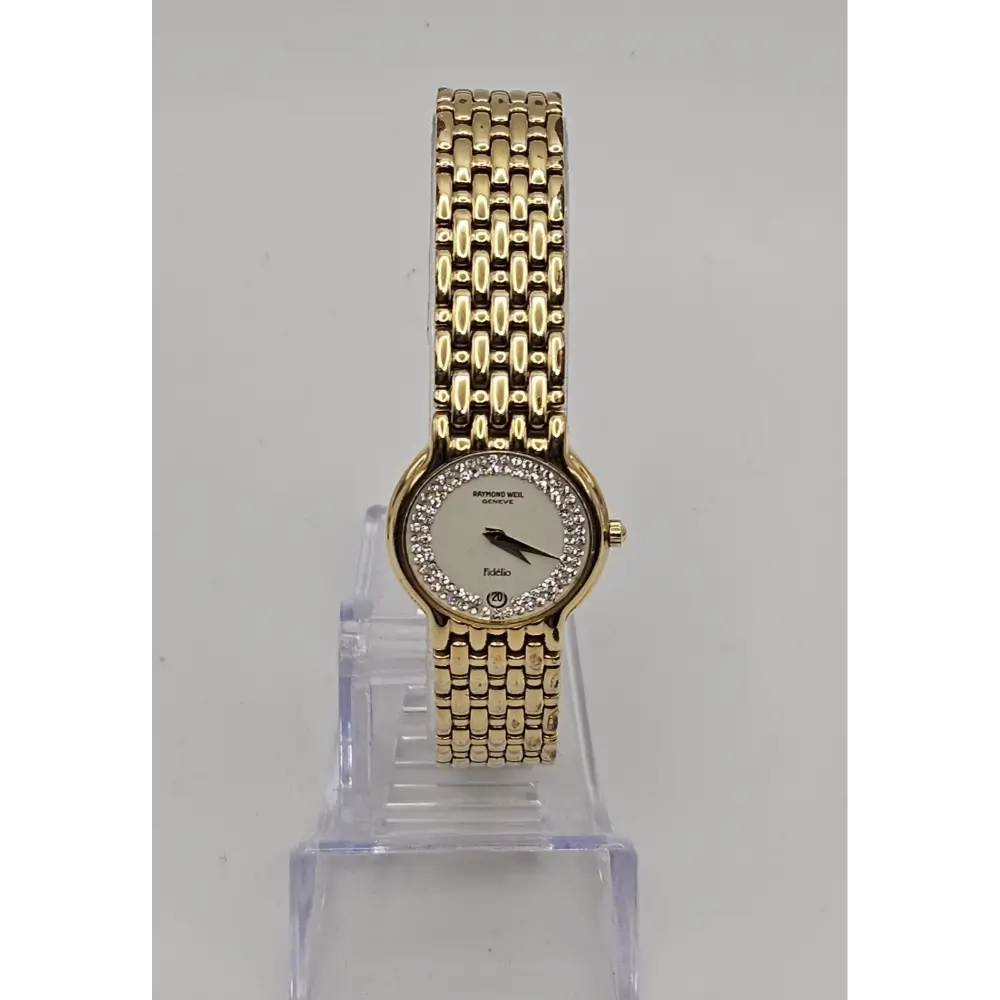 Gold wristwatch with a clear stand on a gray background