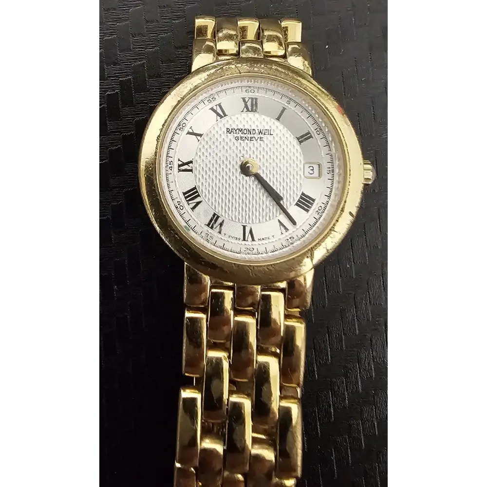 Gold wristwatch with a white face and Roman numerals on a black textured background