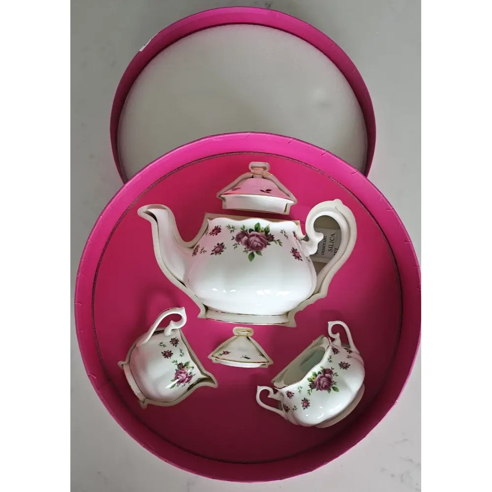 Set of ceramic tea set with floral design on a pink cushioned tray