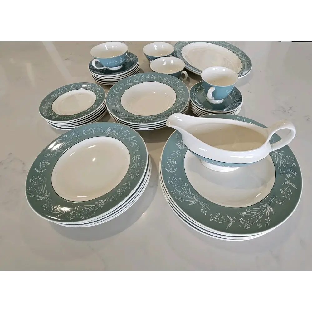 Set of ceramic dinnerware with green and white pattern on a reflective surface