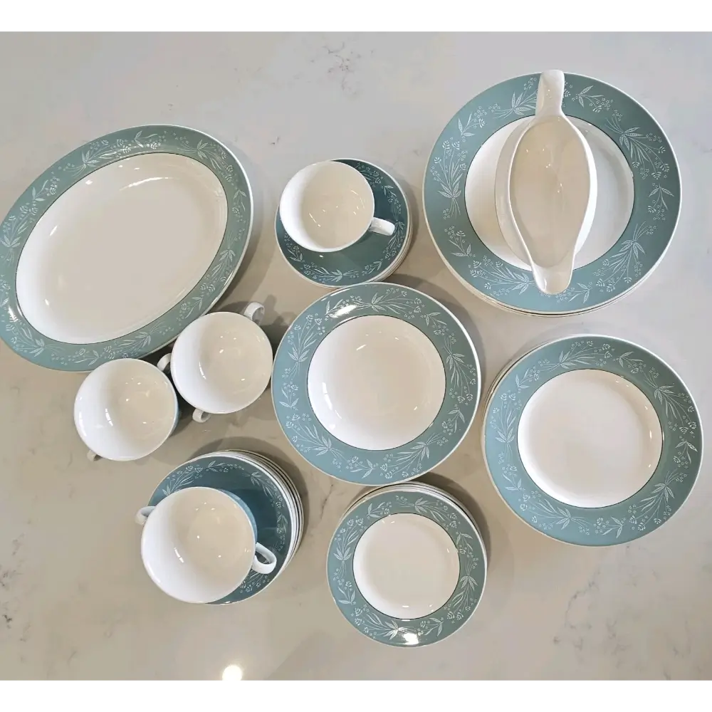 Collection of white ceramic dishes with green decorative rims on a light gray surface.