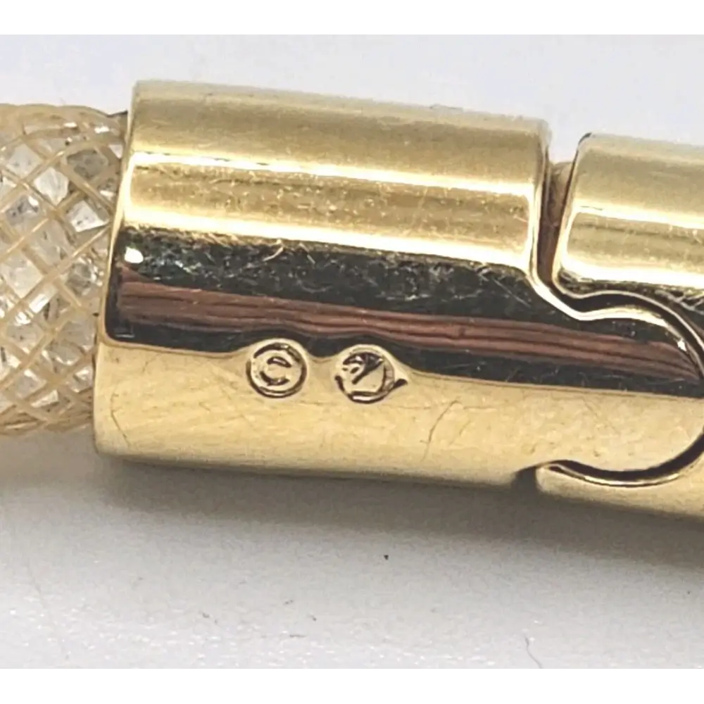 Close-up of a gold bracelet with intricate design on a white background