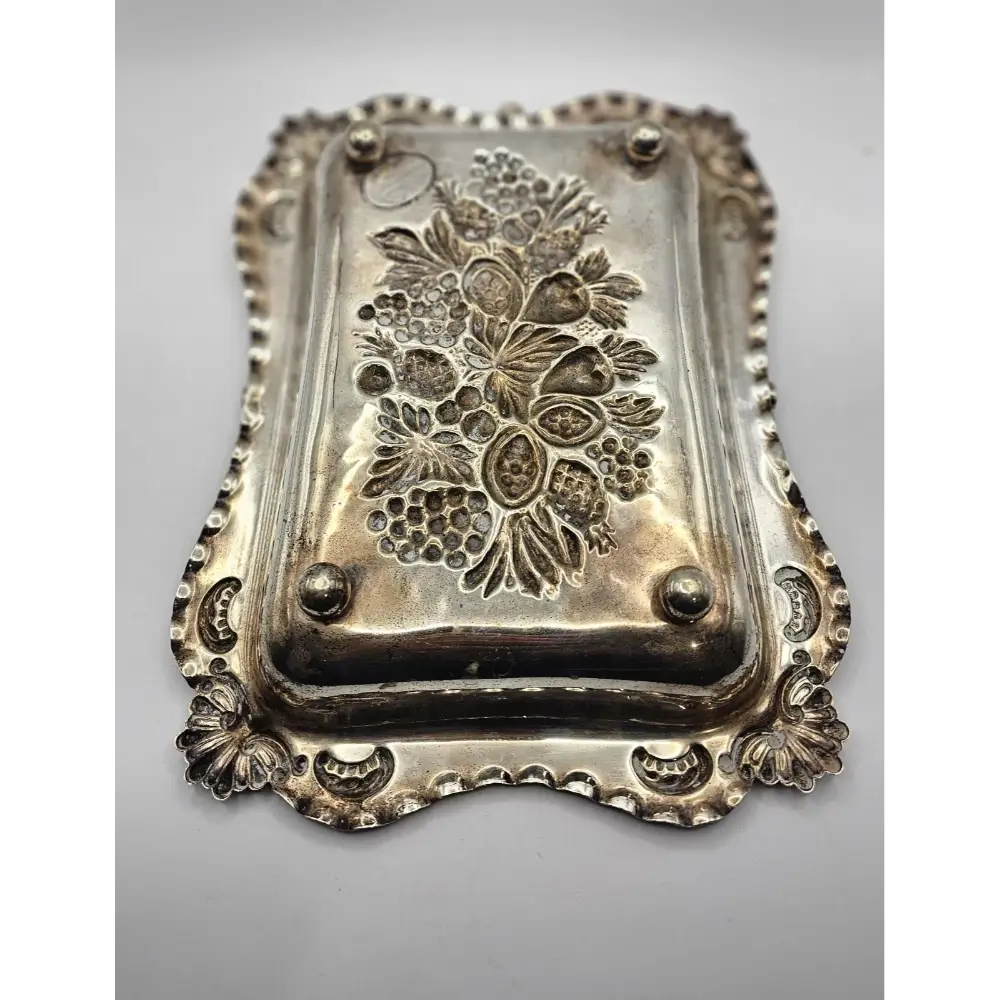 Decorative silver tray with floral patterns on a gray background