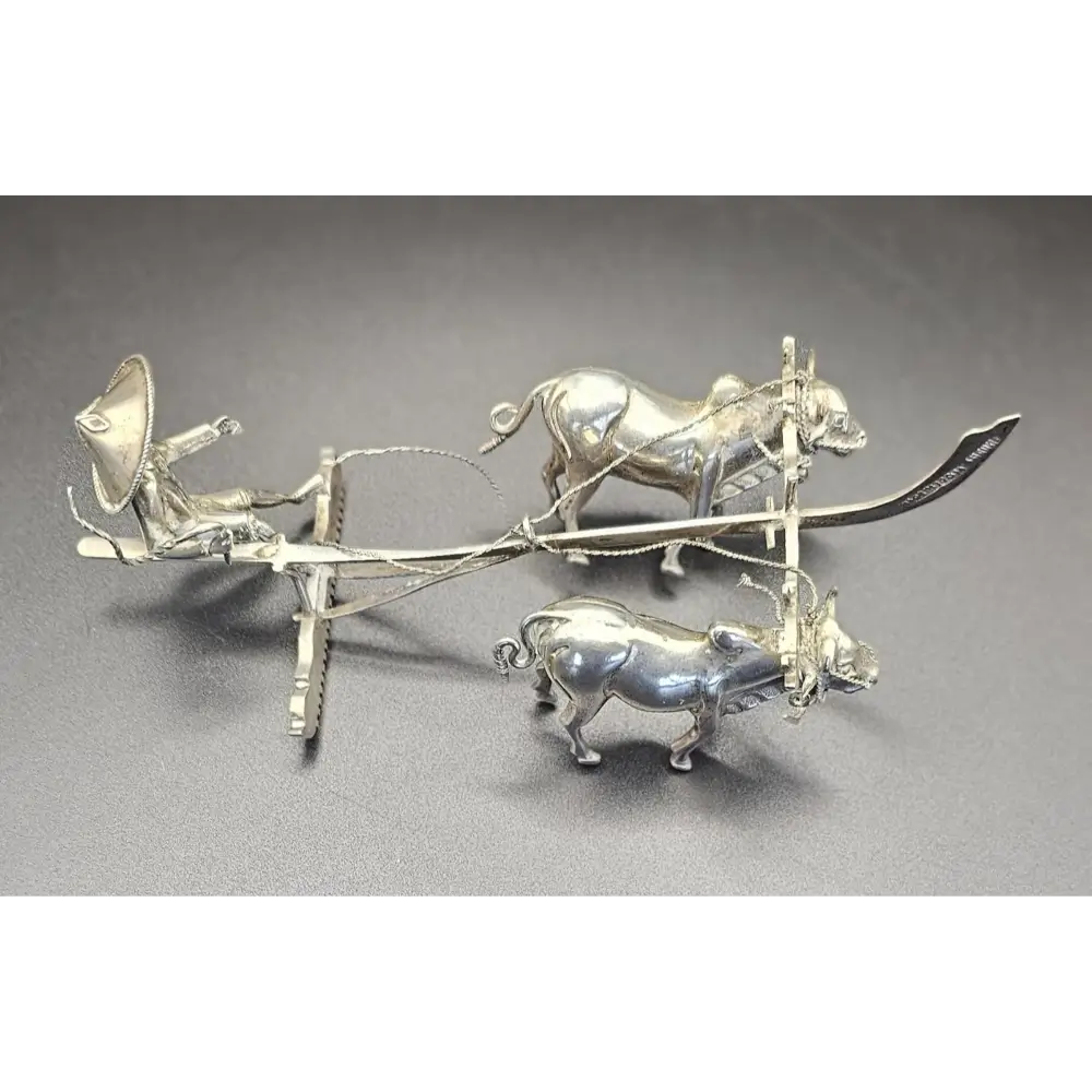 Silver plow with oxen on a gray background