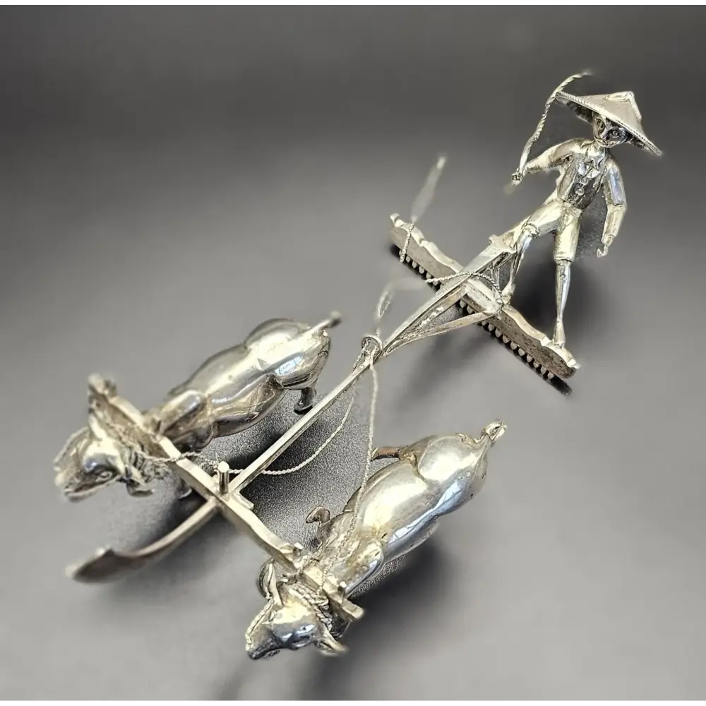 Silver sculpture of a figure on a horse with a gray background