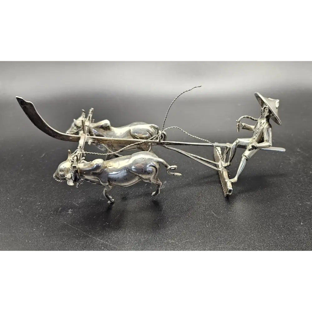 Silver sculpture of a farmer on a cart with two oxen