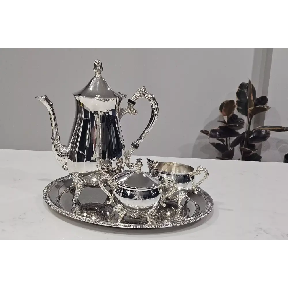 Silver tea set with teapot, creamer, sugar bowl, and tray on a white surface.