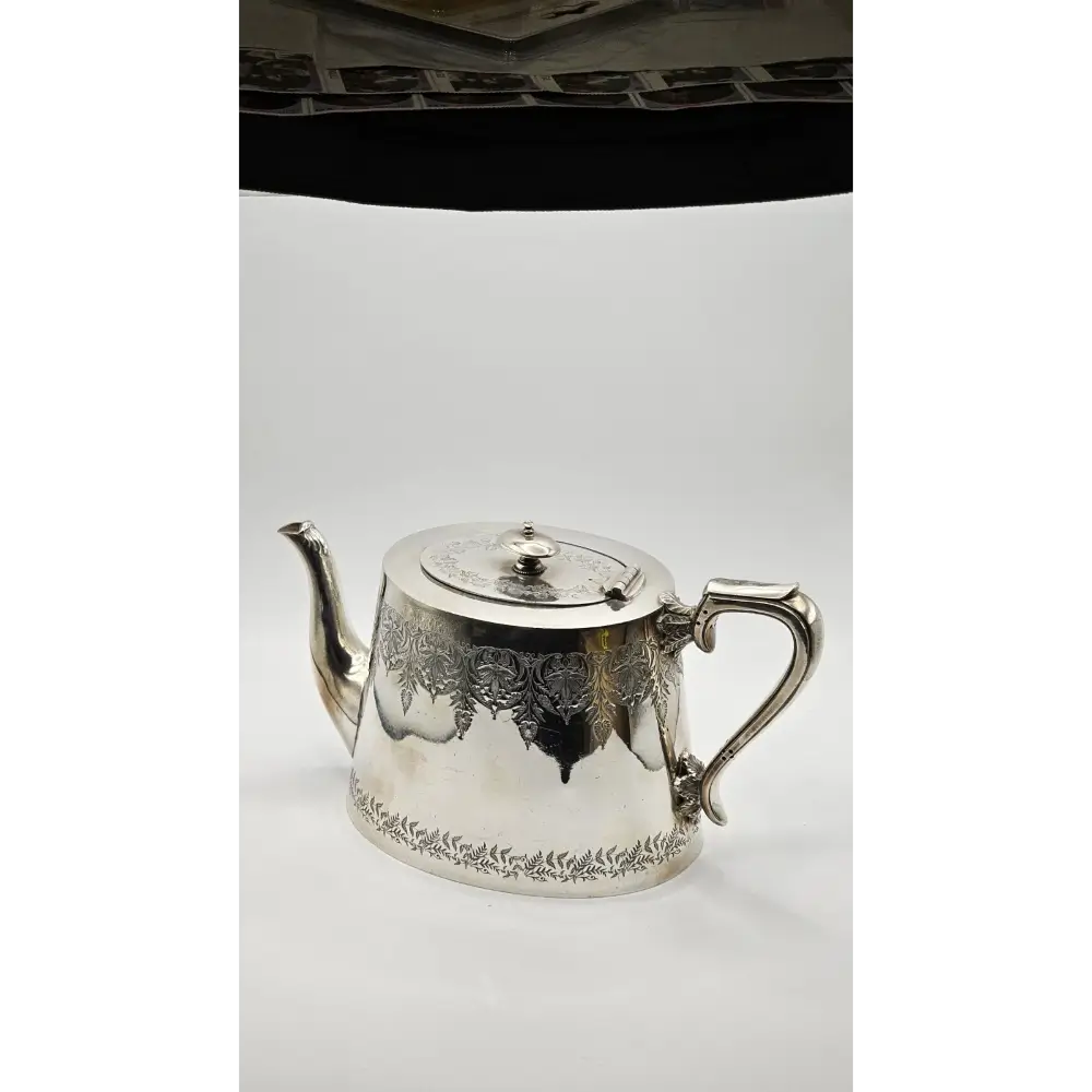 Silver teapot with intricate designs on a white background