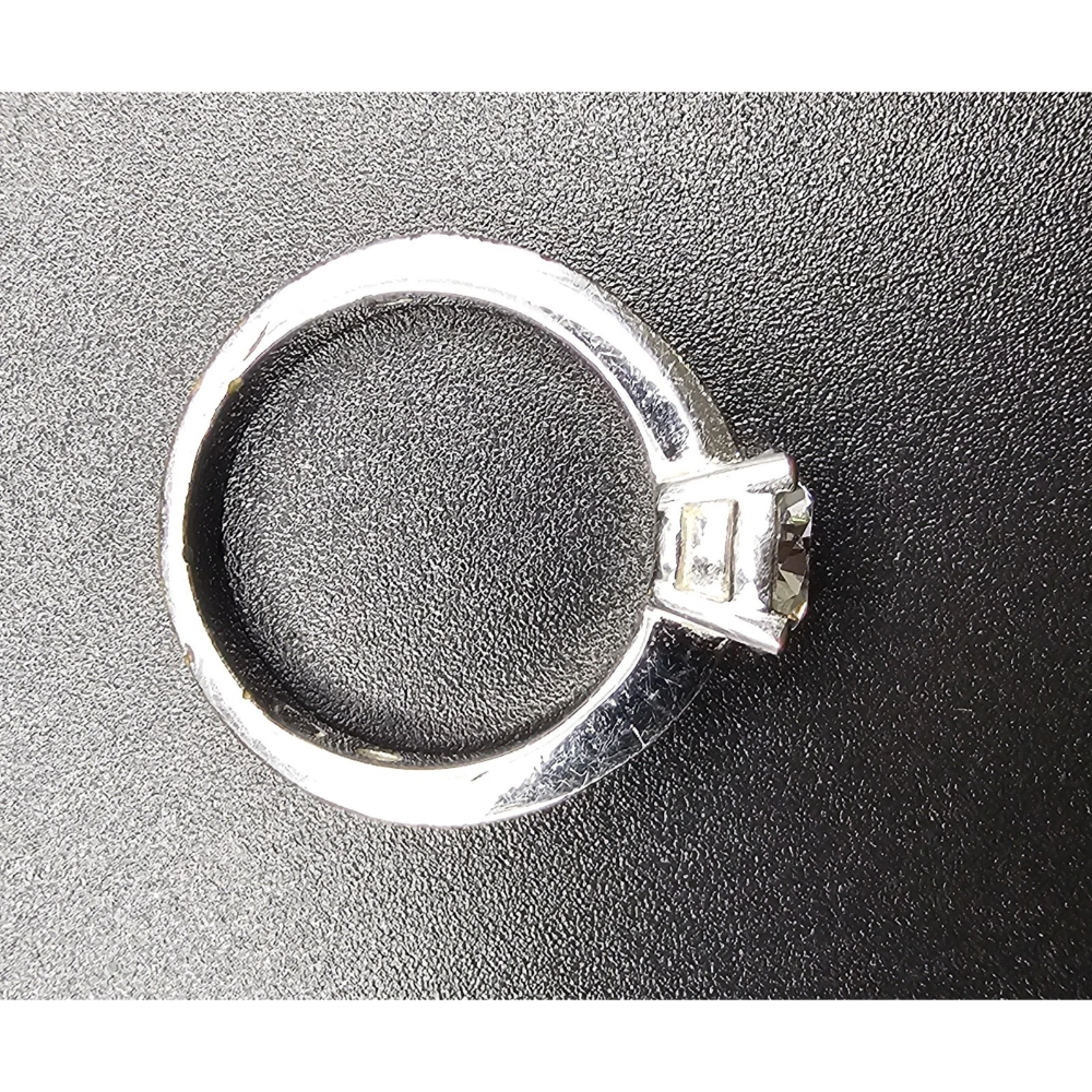 Silver ring with a diamond on a black background