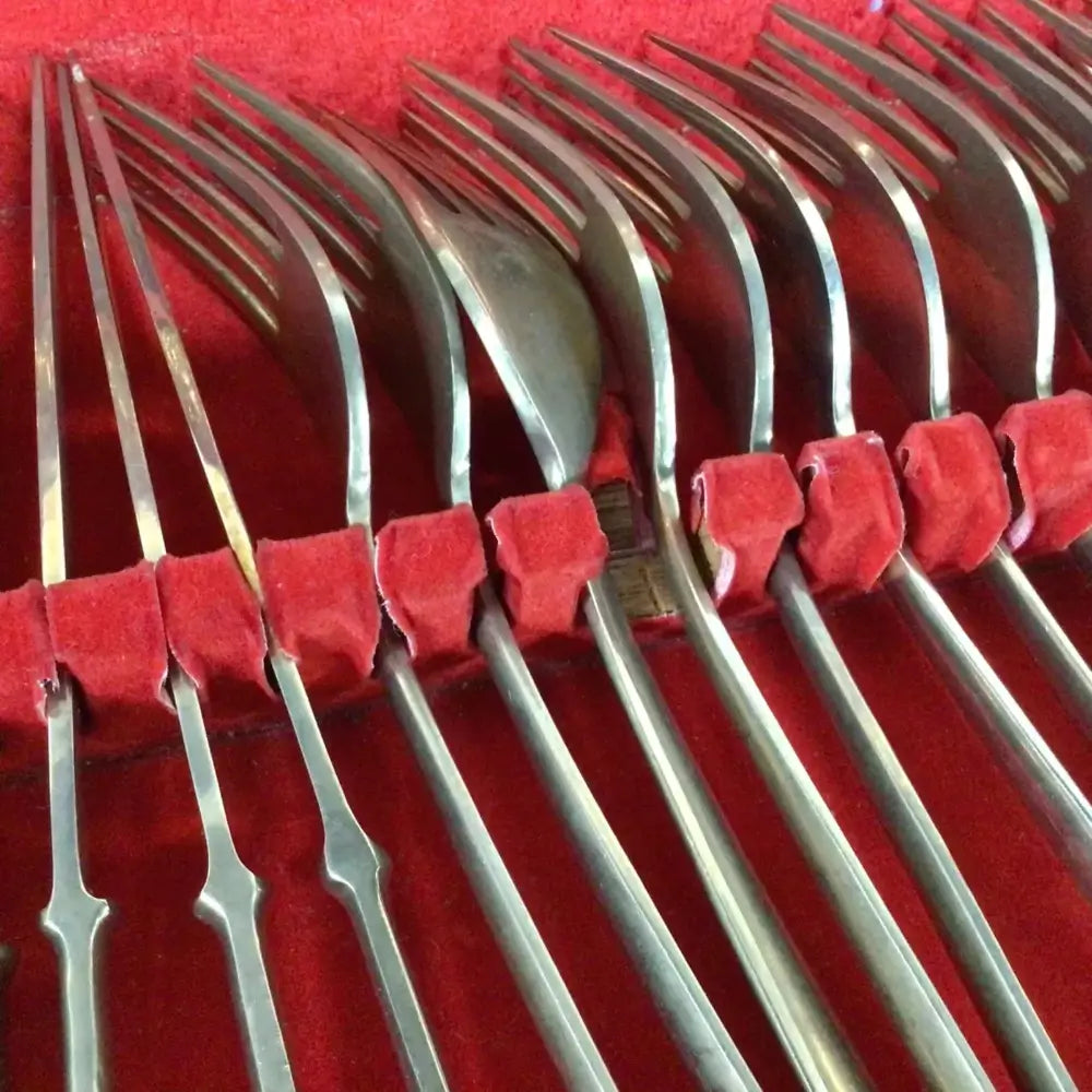 Set of silver dessert forks on a red cushion
