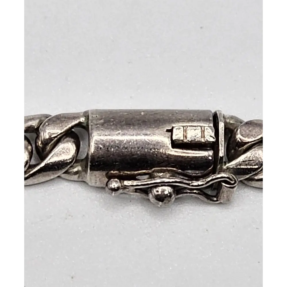 Close-up of a silver bracelet clasp on a light gray background